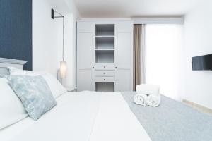 a white bedroom with a white bed with two towels at Zeus Village Resort - Adults Only in Kato Daratso