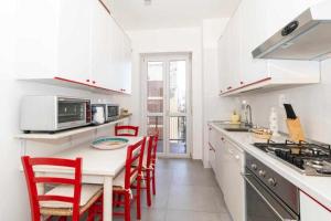 a white kitchen with red chairs and a table at Appartamento Turati 74 in Turin