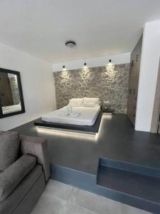 Rock N Sun - Brand new apartment in Ermioni في إرميوني: غرفة نوم بسرير واريكة في غرفة