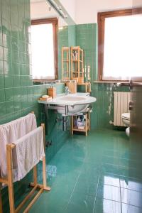 La salle de bains est pourvue d'un lavabo et d'un mur carrelé vert. dans l'établissement S255 - Sirolo, nuovo trilocale a due passi dal centro, à Sirolo