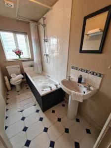 a bathroom with a tub and a sink and a toilet at Goodwins' by Spires Accommodation a comfortable place to stay close to Burton-upon-Trent in Swadlincote