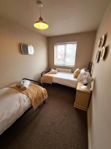 a bedroom with two beds and a window at Goodwins' by Spires Accommodation a comfortable place to stay close to Burton-upon-Trent in Swadlincote