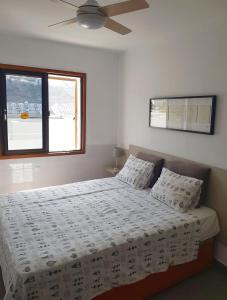 a bedroom with a white bed with a ceiling fan at Relax Arimar Apartment Puerto Rico in Puerto Rico de Gran Canaria