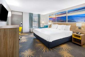 a hotel room with a bed and a flat screen tv at Days Inn by Wyndham Roanoke Near I-81 in Roanoke
