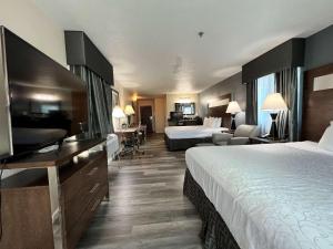 a hotel room with two beds and a flat screen tv at Best Western Americana in Dinuba +13 photos
