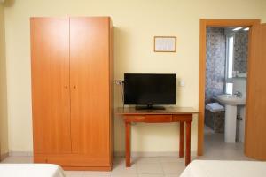 a room with a desk with a television and a cabinet at Hostal Restaurante El Paso in Bailén