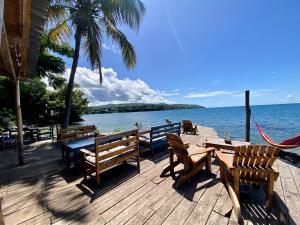a wooden deck with benches and tables and the ocean at Butterfly Space- A Non-Profit Eco-Lodge in Nkhata Bay