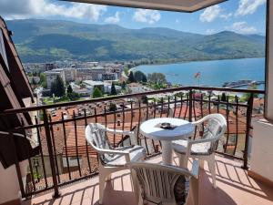 a balcony with a table and chairs and a view of the water at Villa Mesokastro in Ohrid