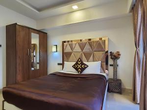 a bedroom with a large bed with a wooden headboard at OSI Apartments BKC Kurla West in Mumbai