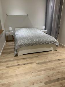 a bedroom with a bed and a wooden floor at Bel appartement en coeur de ville - 20 minutes du PAL in Moulins