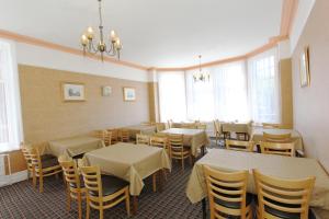 a dining room with tables and chairs and windows at West Point Hotel Bed and Breakfast in Colwyn Bay