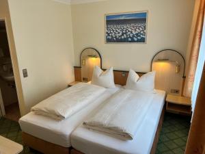 2 Betten in einem Hotelzimmer mit weißen Kissen in der Unterkunft Parkhotel Crombach in Rosenheim