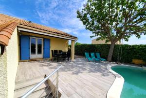 une terrasse avec une piscine et des chaises à côté d'une maison dans l'établissement Villa du soleil, piscine, à 10 mins de Montpellier, à Vendargues
