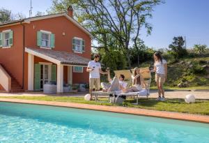 a group of people standing around a pool in front of a house at Villa LeMarche b&b in Rustico