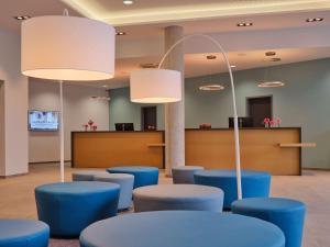 une salle d'attente avec des tables et des tabourets bleus dans l'établissement Dorint Parkhotel Frankfurt / Bad Vilbel, à Bad Vilbel