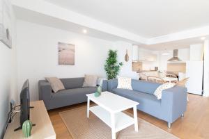 ein Wohnzimmer mit einem blauen Sofa und einem Tisch in der Unterkunft Global Properties, Apartamento nuevo en la playa de Canet d'en Berenguer in Canet d'en Berenguer
