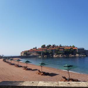 a beach with tables and chairs and umbrellas at Vila Horizont in Sveti Stefan