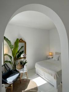 una camera bianca con un letto e una sedia di Islander House ad Agios Georgios