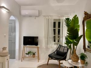 un soggiorno con sedia nera e TV di Islander House ad Agios Georgios
