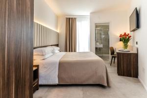 a bedroom with a bed and a desk with a television at Hotel Falli in Porto Cesareo