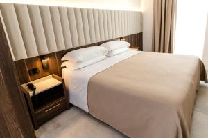 1 dormitorio con 1 cama grande con sábanas y almohadas blancas en Hotel Falli, en Porto Cesareo