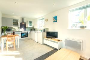 a kitchen with white cabinets and a wooden table at Rockpool - Bude in Bude