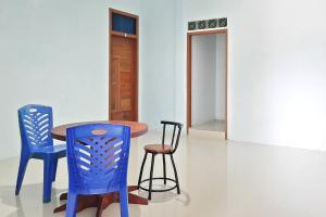 einen Tisch und zwei blaue Stühle in einem Zimmer in der Unterkunft Prima Homestay Mentawai Mitra RedDoorz in Tua Pejat