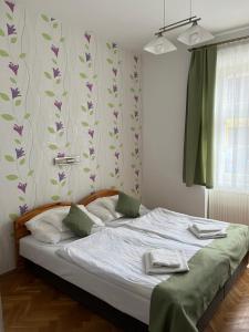 Schlafzimmer mit einem Bett mit weißer Bettwäsche und lila Blumen in der Unterkunft Vaskapu Fogadó in Vasvár
