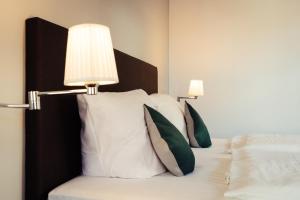 Una cama con almohadas blancas y una lámpara. en Zum Schwan Wanfried, en Wanfried