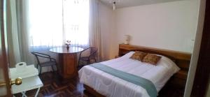 1 dormitorio con cama, mesa y ventana en Samadri, en Arequipa