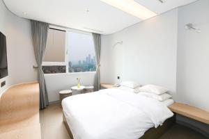 a white bedroom with a large bed and a window at Hotel The Designers Hongdae in Seoul