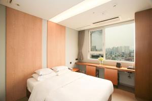 a bedroom with a bed and a desk and a window at Hotel The Designers Hongdae in Seoul
