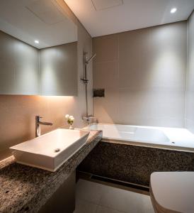 a bathroom with a sink and a bath tub at Hotel The Designers Hongdae in Seoul