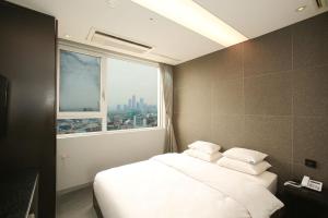 a bedroom with a large white bed with a window at Hotel The Designers Hongdae in Seoul