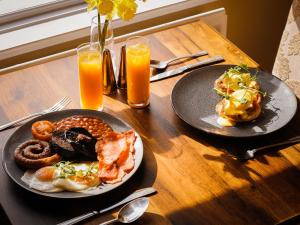 a wooden table with two plates of food and orange juice at Buttermere Court Hotel in Buttermere