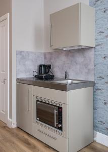 cocina blanca con fregadero y microondas en Modern Studio Apartments en Londres