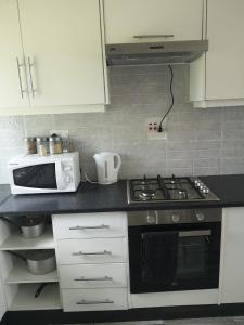 a kitchen with a stove and a microwave at Sheila's Cottage in Lusaka