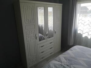 a bedroom with a white cabinet and a bed at Sheila's Cottage in Lusaka