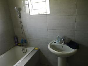 un bagno bianco con lavandino, vasca e lavandino di Sheila's Cottage a Lusaka