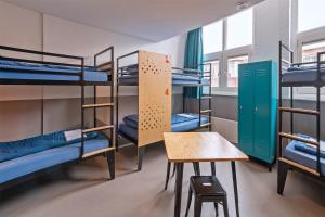 Ce dortoir comprend des lits superposés et une table. dans l'établissement Stayokay Hostel Den Haag, à La Haye