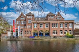 ein großes Backsteingebäude neben einem Wasserkörper in der Unterkunft Stayokay Hostel Den Haag in Den Haag