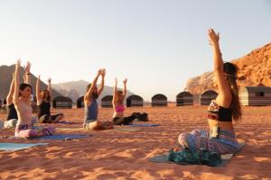 a group of women doing yoga on the beach at Bedouin desert camp in Wadi Rum