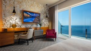 a hotel room with a desk and a large window at Royal Ariston Hotel in Dubrovnik