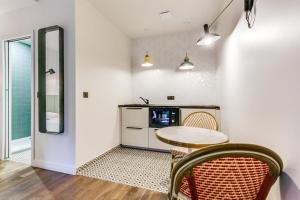 Zimmer mit einem Tisch, Stühlen und einer Mikrowelle in der Unterkunft Le Vert Galant - Auberge Etchegorry in Paris