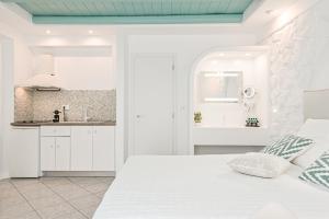 a white bedroom with a white bed and a kitchen at Naxos Evilion Luxury Apartments & Suites in Naxos Chora