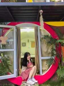 Una chica sentada en una ventana de una casa en MŨM HOMESTAY MỘC CHÂU, en Mộc Châu