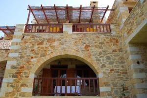 - un bâtiment en pierre avec un balcon et une arche dans l'établissement Golden Sun Apartments, à Falasarna