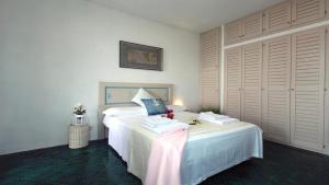 a bedroom with a bed with white sheets and pillows at Grecalotto Apartment in La Maddalena