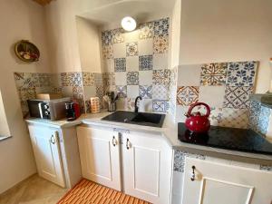 uma cozinha com armários brancos e um lavatório e azulejos em Casa Vacanze Cascina Mombello em Sinio
