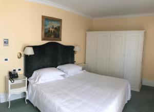 a bedroom with a large white bed with a black headboard at Hotel Riviera & Maximilian's in Trieste